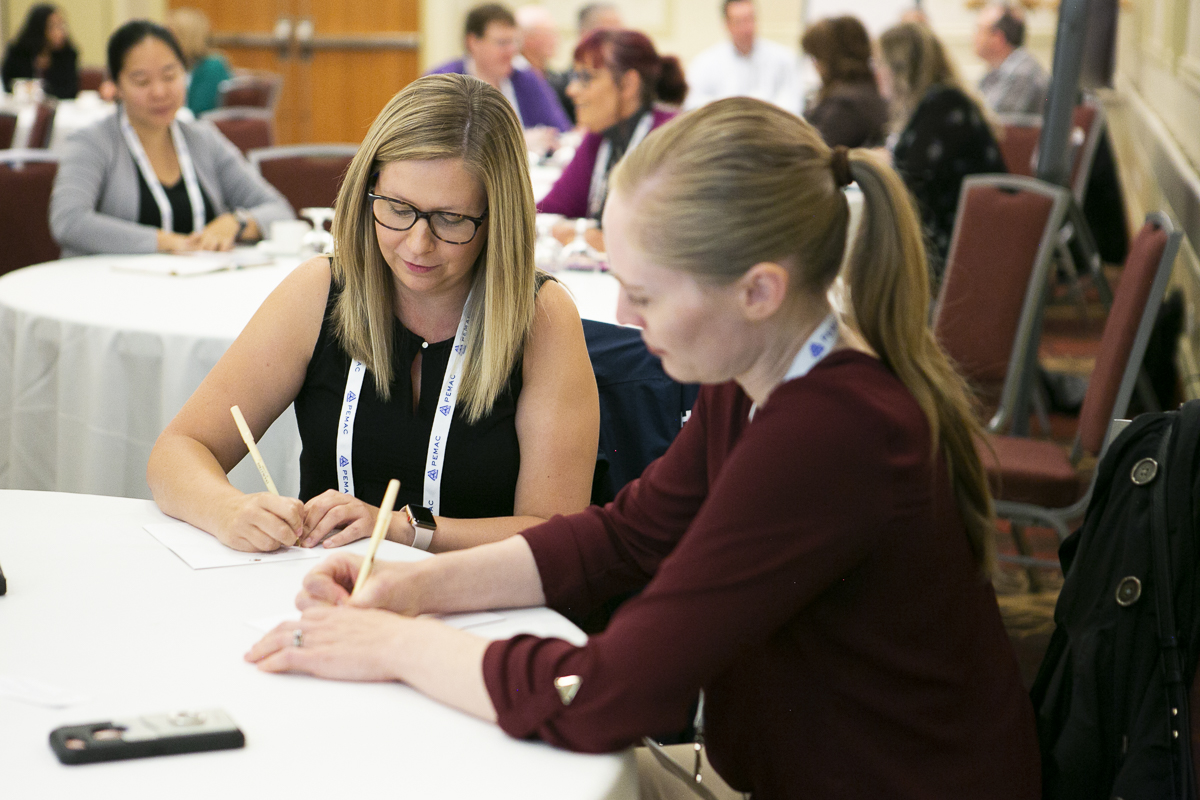 Conference participants taking diligent notes during a session