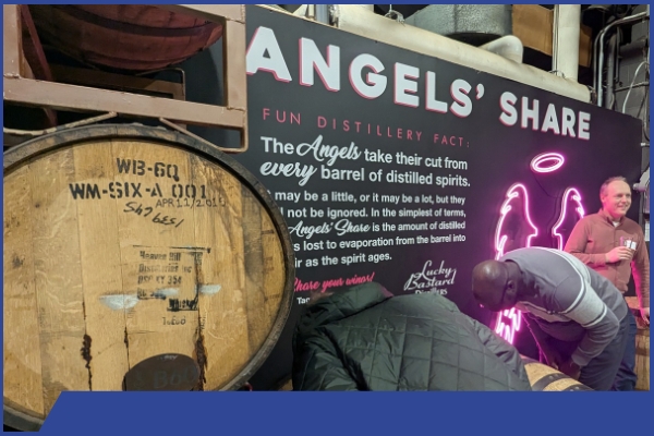 PEMAC Members inspect a barrel in front of a sign that explains what "the Angels Share" is.